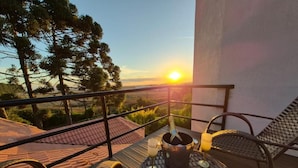 Ein Balkon mit Blick auf den Sonnenuntergang, ein Tisch mit Flasche und Gläsern sowie zwei Stühle.