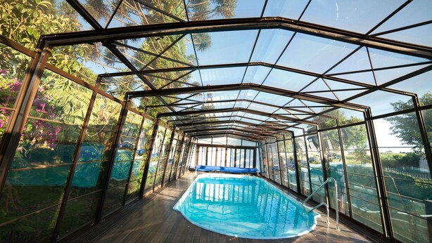 Ein von Glas umgebener Pool mit Holzterrasse und Metallgeländern.