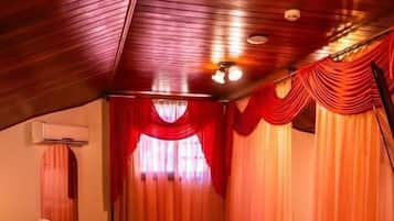 Una habitació acollidora amb sostre de fusta, un llit amb col·cha amb motius florals, una taula petita i una cadira.