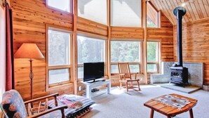 A cozy cabin interior with wooden walls, a fireplace, a television, and a comfortable seating area. - Red Fox Retreat (Yosemite)