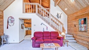 A spacious living area with a red sofa, wooden coffee table, and a staircase leading to an upper level. - Red Fox Retreat (Yosemite)