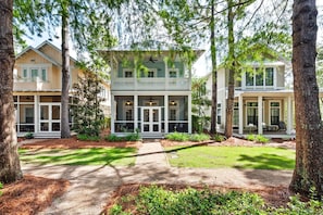 A two-story house with a porch, surrounded by trees and a well-maintained lawn.
