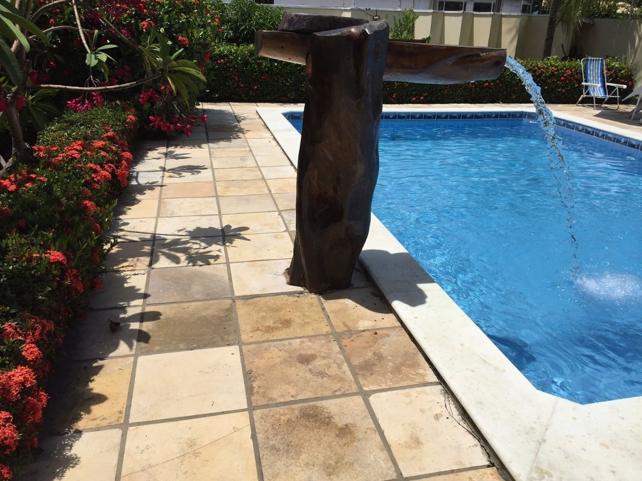 A swimming pool with a wooden structure and red flowers.