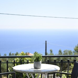 Una mesa redonda con una planta en maceta en un balcón con vista al mar.