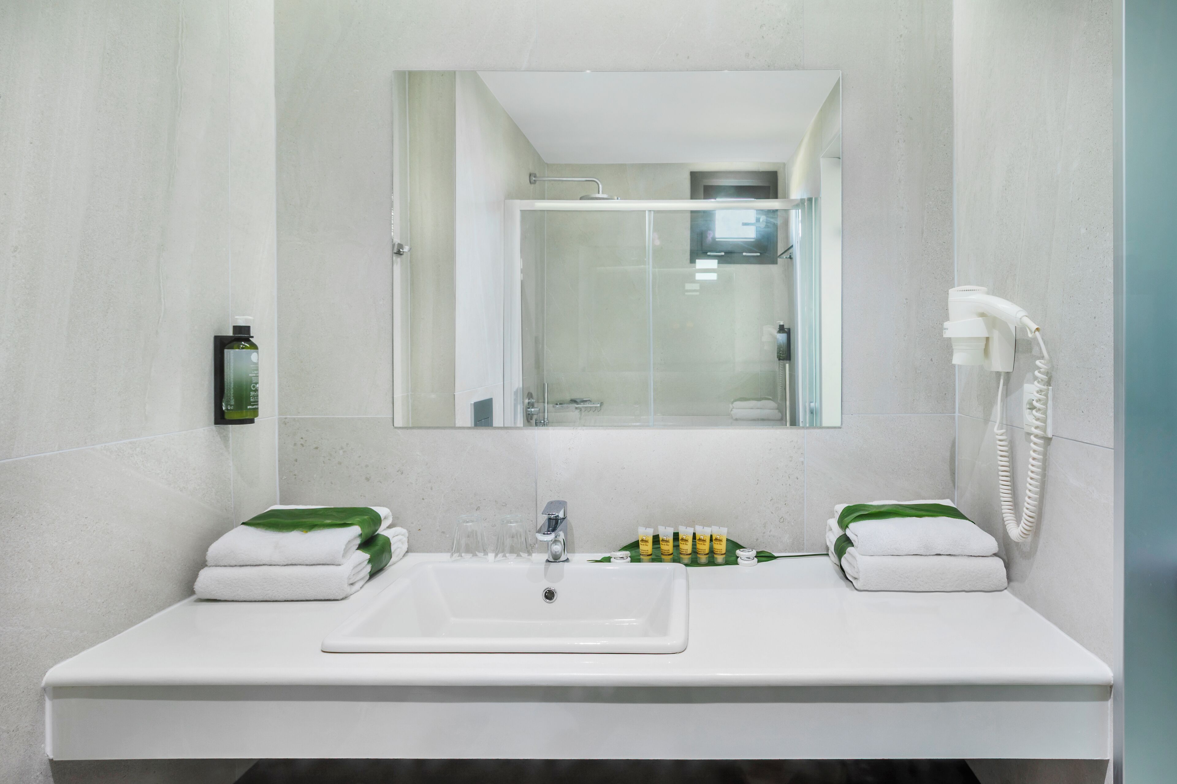 A bathroom with a white sink, two towels, a glass shower enclosure, and a telephone.