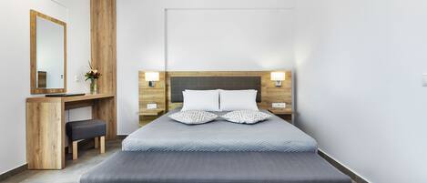 Un dormitorio moderno con cama, mesitas de noche, un escritorio y un espejo.