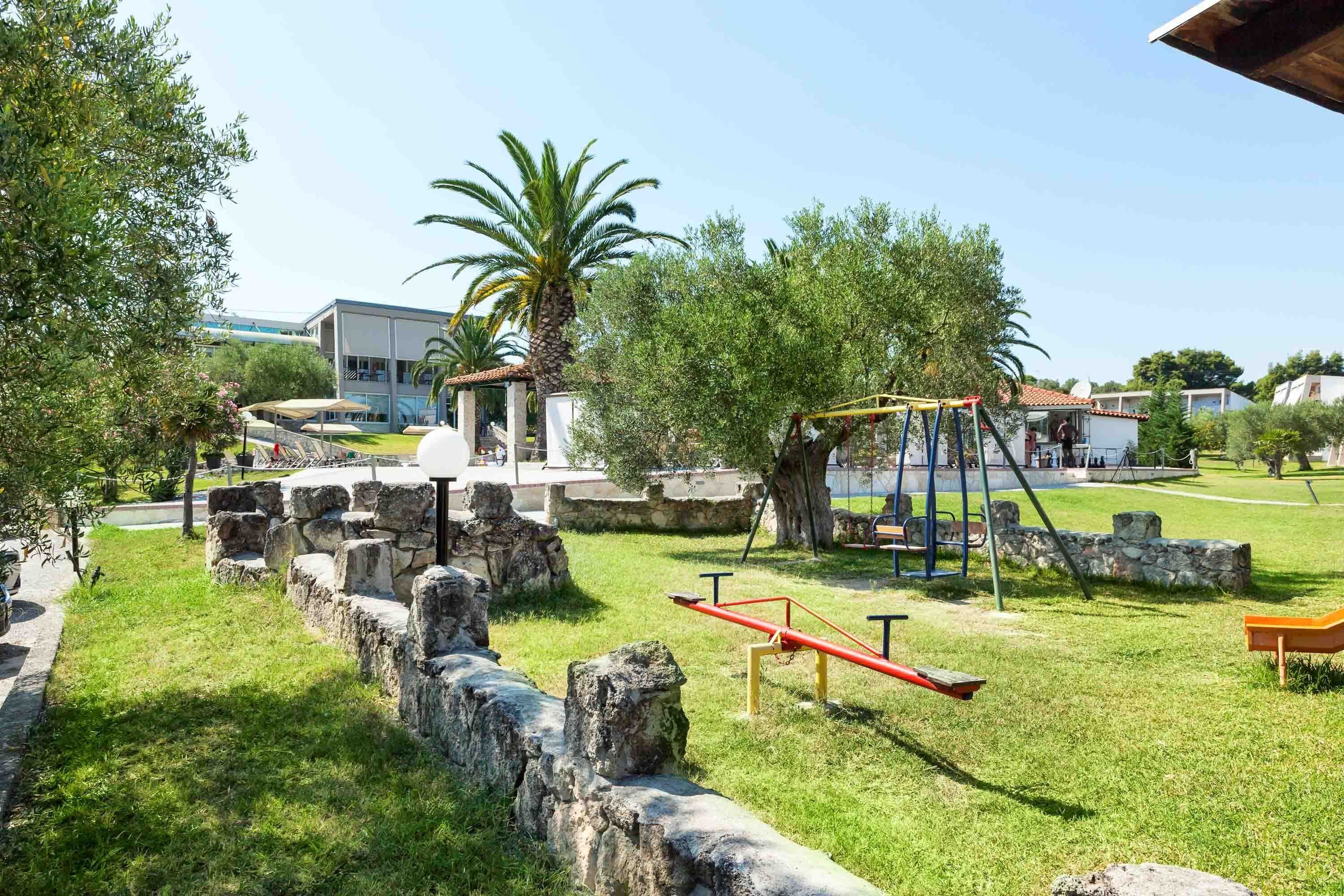 A park with a seesaw, stone walls, and a palm tree.