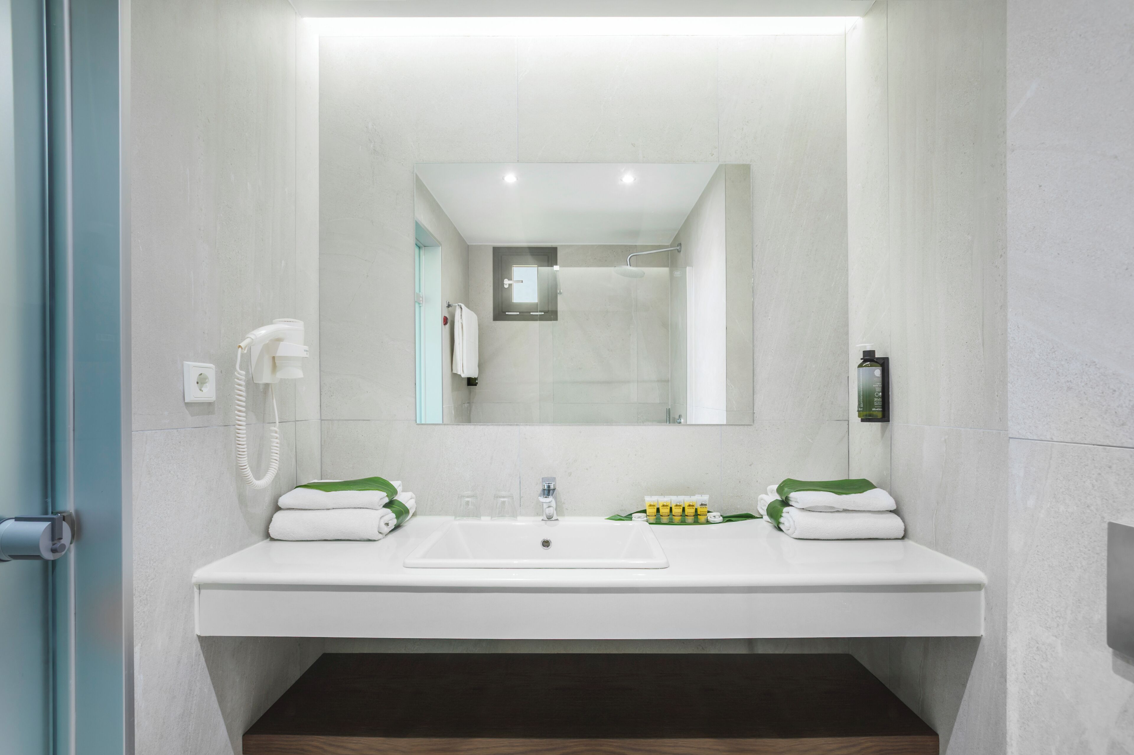 A modern bathroom with a white sink, two towel racks, a glass shower enclosure, and a mirror above the sink.