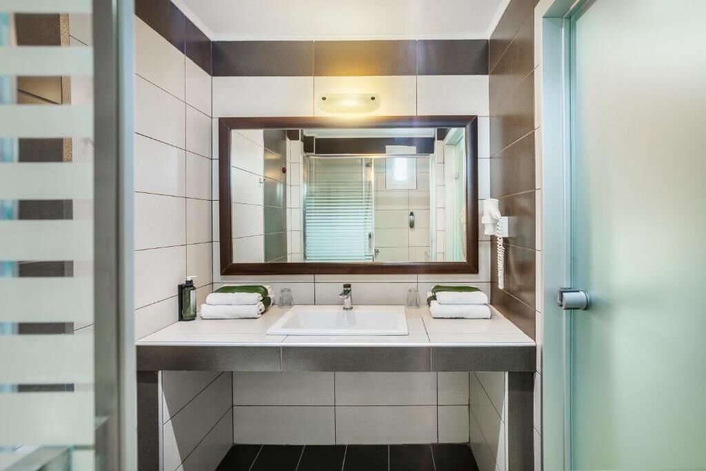 Un baño moderno con dos lavamanos, un espejo grande y un perchero para toallas.