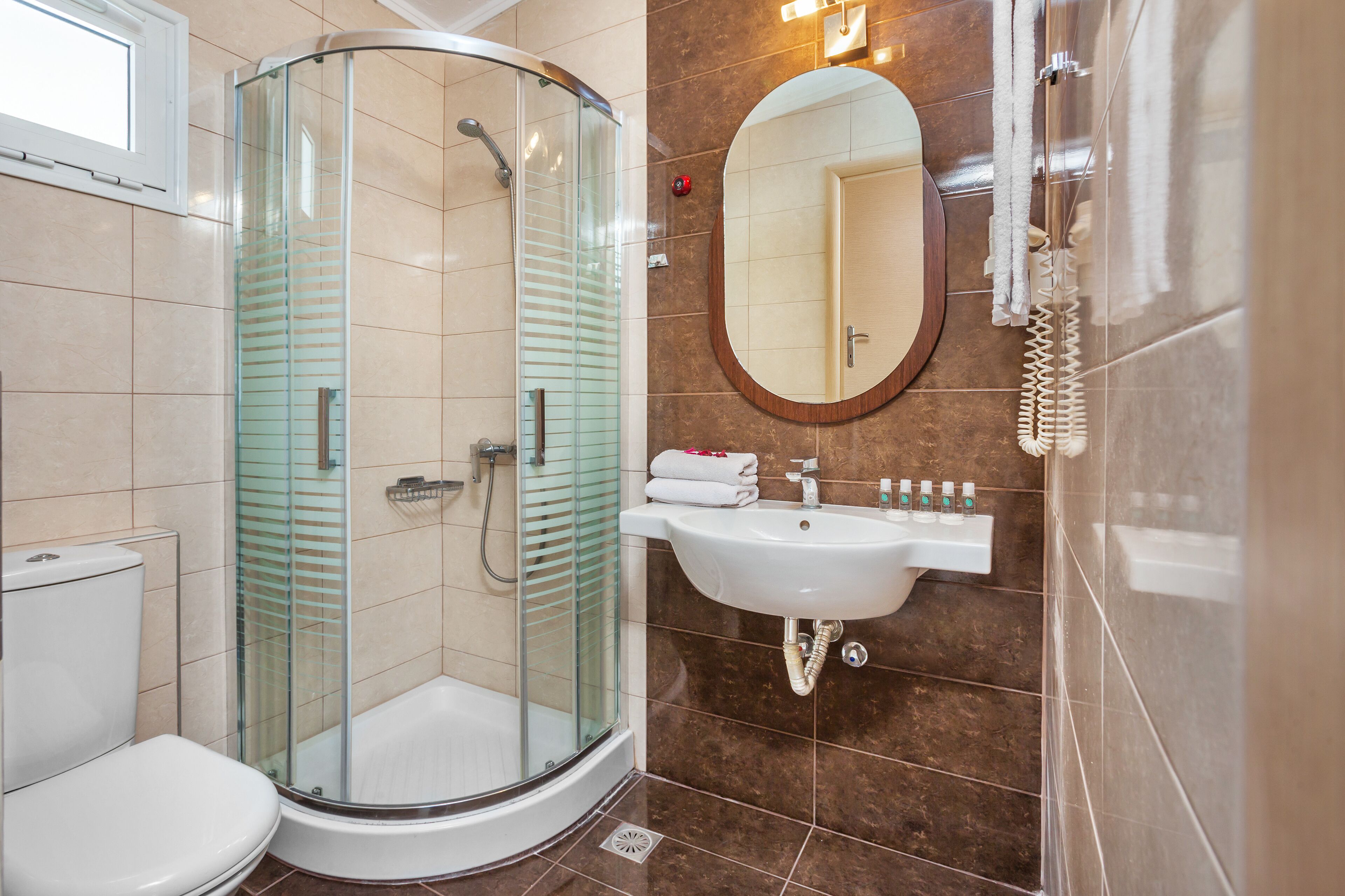 A modern bathroom with a glass-enclosed shower, a white sink, and a large mirror.