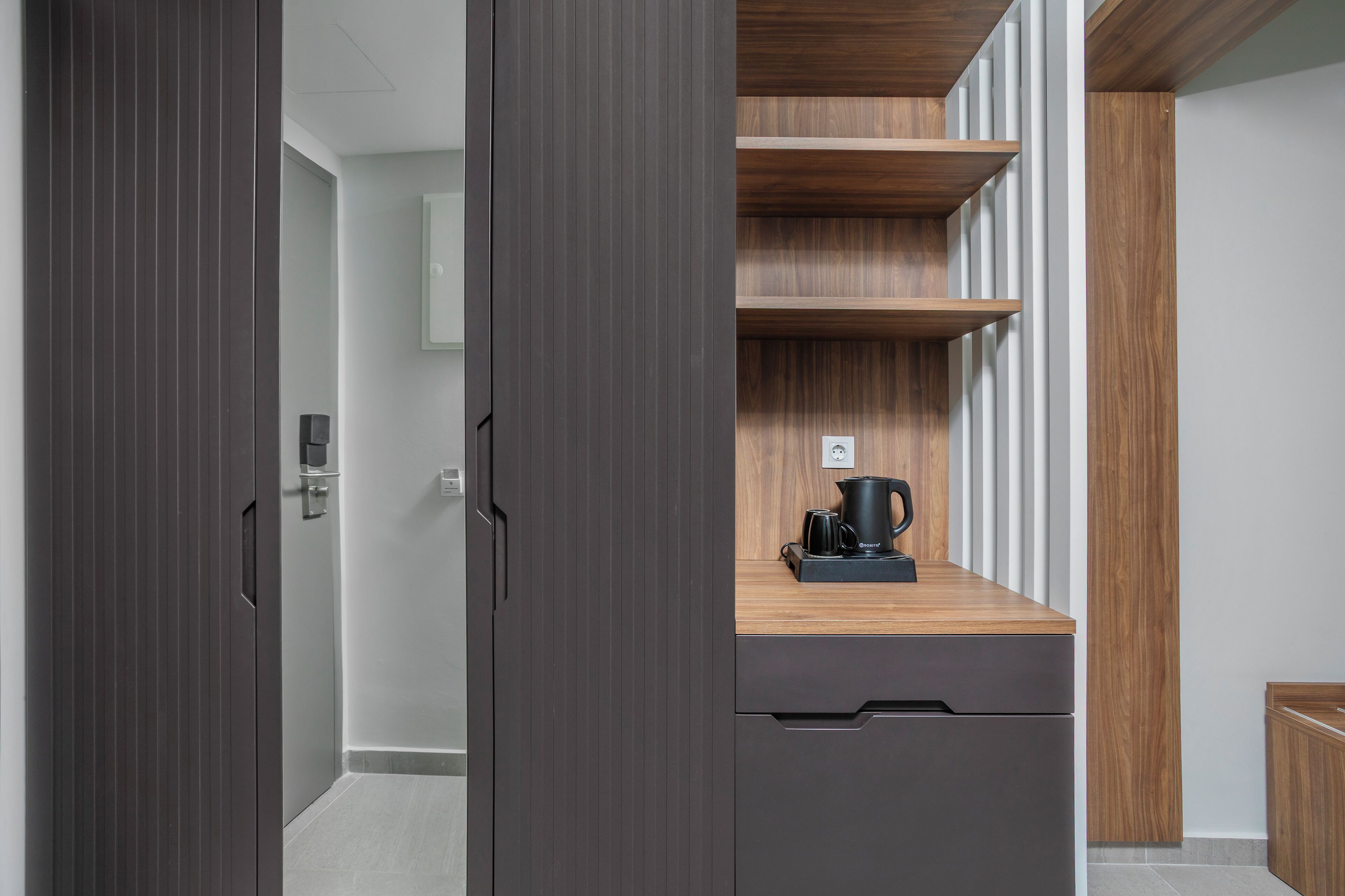 A modern kitchen with dark cabinetry, a wooden countertop, and a coffee maker.