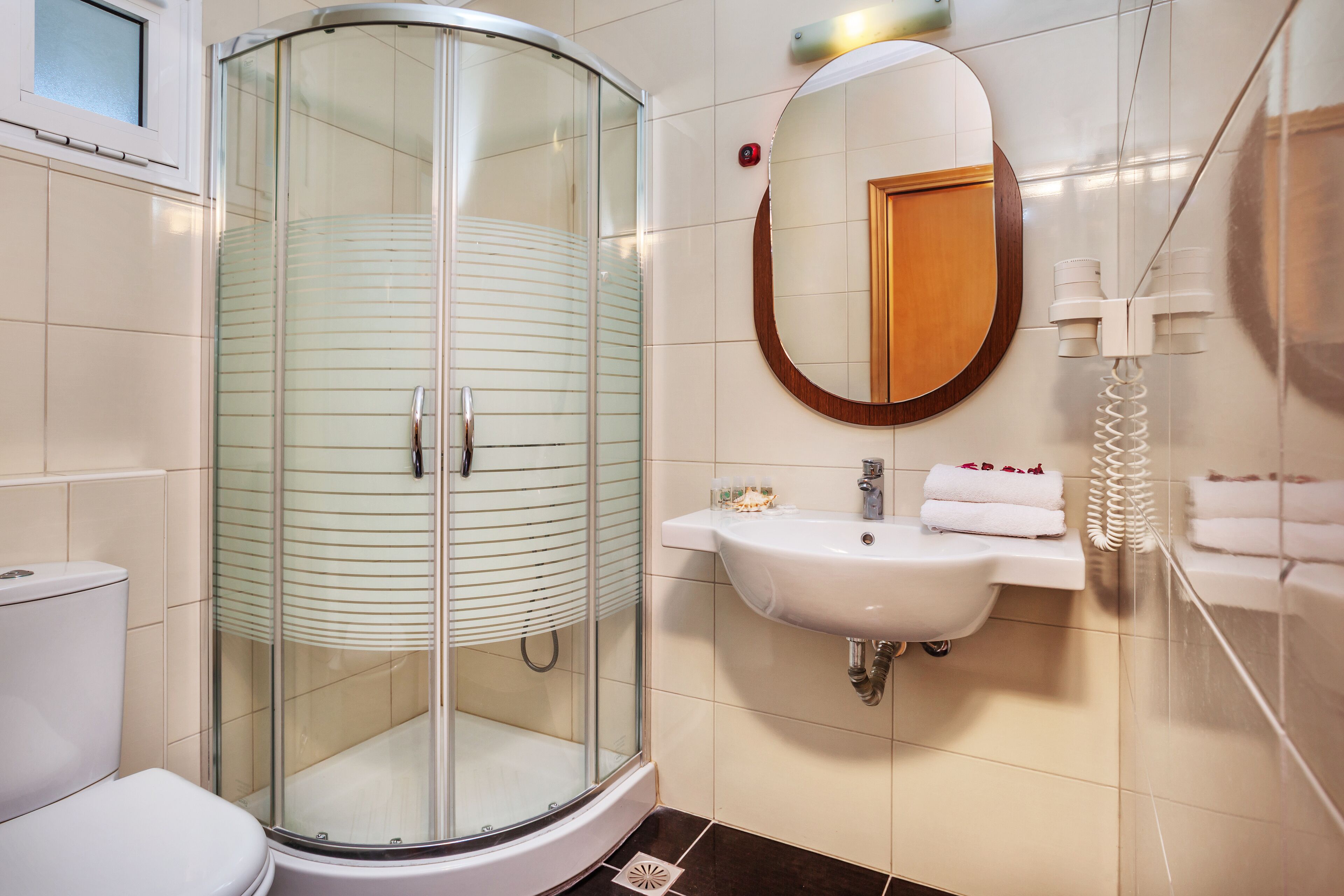 A bathroom with a glass-enclosed shower, a sink with a mirror, and a toilet.
