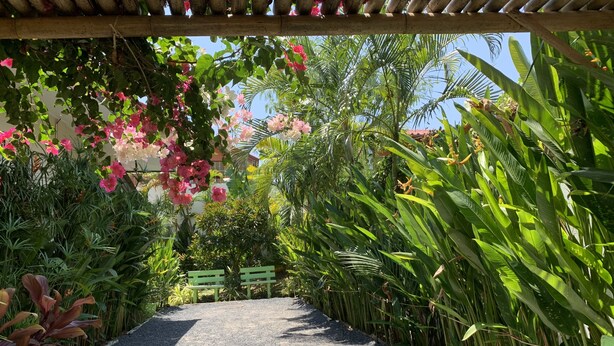 A garden pathway with a checkered table in the foreground, surrounded by lush greenery and flowering plants. - PACOTTE, nice living villa with private (Rawai)