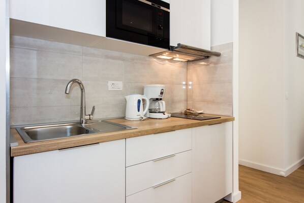 A modern kitchen with a stainless steel sink, a coffee maker, and a microwave.
