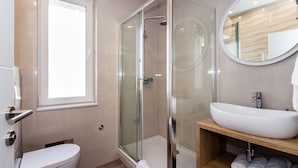 Une salle de bain moderne avec une douche à parois de verre, un lavabo blanc et un meuble-lavabo en bois.