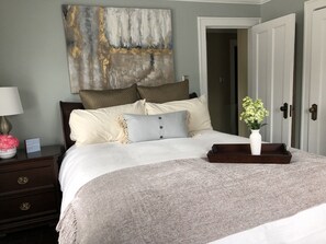 Cozy retreat with a large bed, nightstand, and modern artwork.