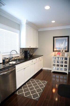 Enjoy cooking in this well-equipped kitchen with a sink, stainless steel dishwasher, and black countertop.