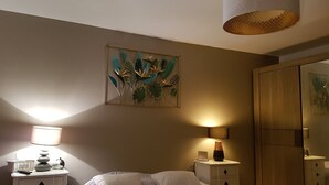 A bedroom with a bed, bedside lamps, a wall-mounted artwork, and a wardrobe.