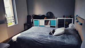 A bedroom with a bed, a window, a desk, and a bookshelf.