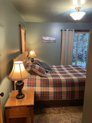 A bedroom with a plaid bedspread, two bedside lamps, a window with curtains, and a framed picture on the wall. - The Adams Chalet perfect for family or friends.  Pet-friendly, Hot tub, WIFI, AC (Randle)