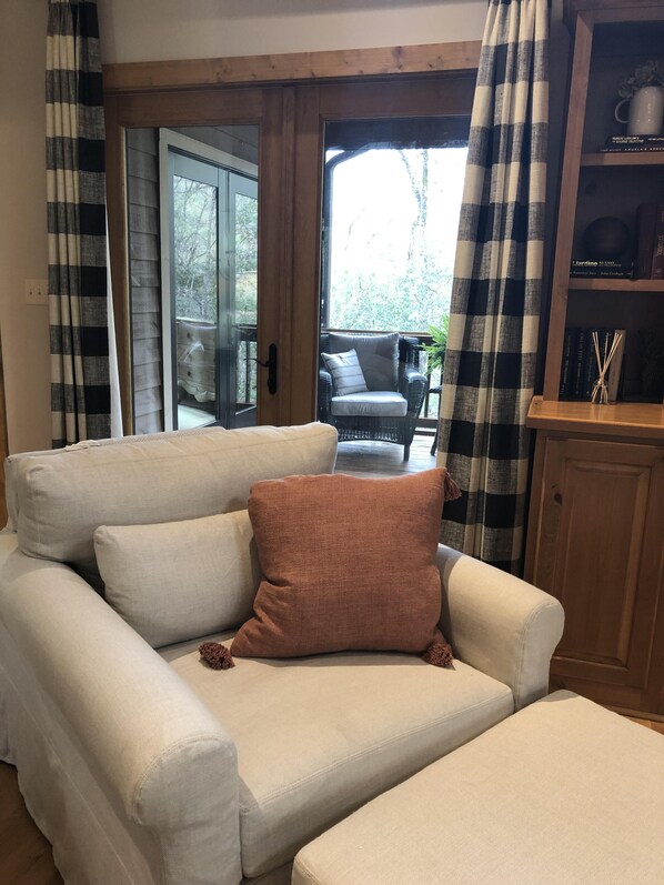A living room with a sofa, a brown cushion, and a bookshelf with books and a vase.