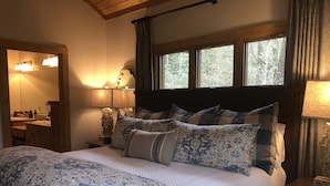 Ein Schlafzimmer mit einem großen Bett, einem hölzernen Kopfteil, einem Nachttisch mit Lampe, einer Kommode und einem Spiegel.