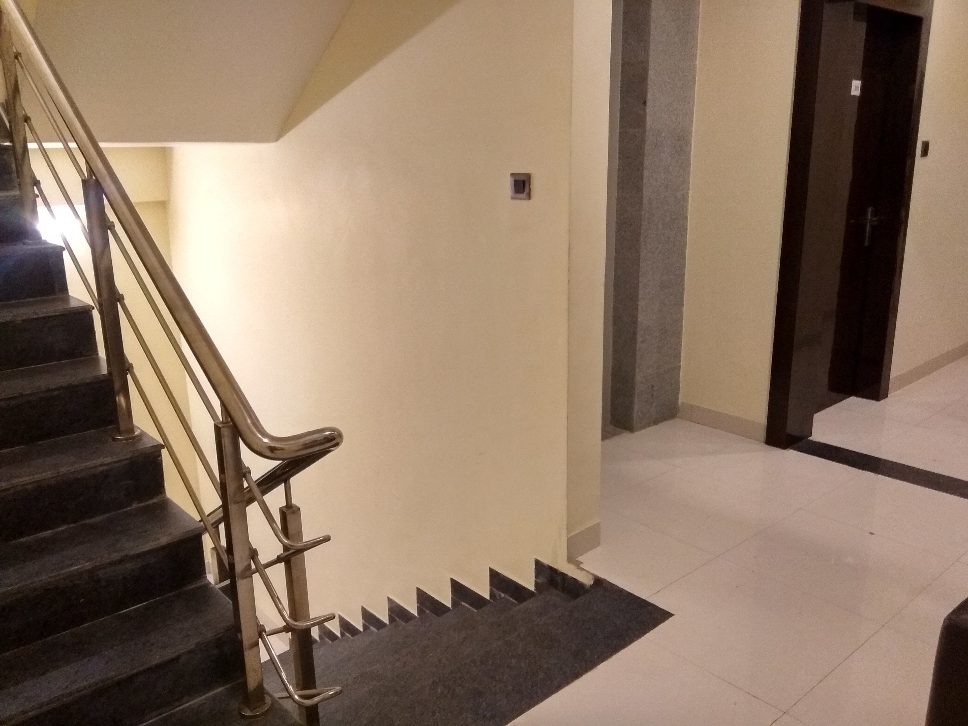 A staircase with metal handrails, a dark carpeted landing, and a tiled floor.