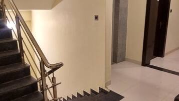 A staircase with metal handrails, a dark carpeted landing, and a tiled floor.