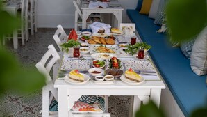 A dining area with a white table set for a meal, surrounded by chairs. - Hotel Lime Bozcaada (Bozcaada)