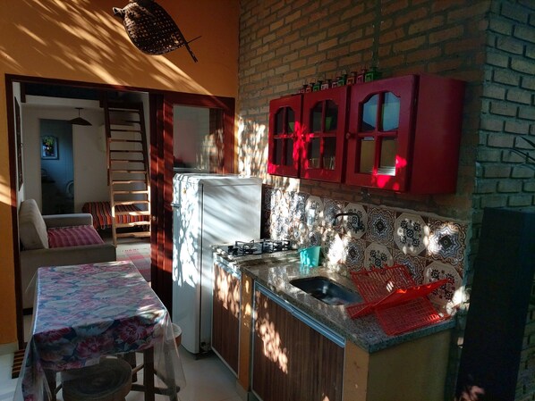 Een koelkast, een kookplaat, kookgerei, borden en bestek