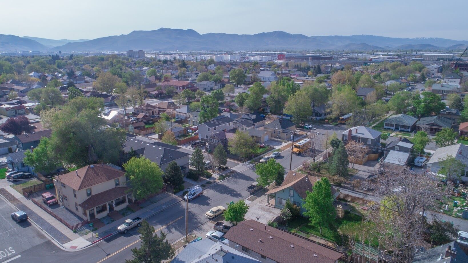 Vista aérea de una zona residencial con casas, calles y una cadena montañosa distante.