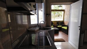 A modern kitchen with a stainless steel sink, a built-in oven, and a window overlooking a garden. - Casa Rinconeda Promotion from August 1 to 13 (Polanco)