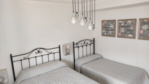 A bedroom with two beds, a chandelier, and floral wall art. - Casa Rinconeda Promotion from August 1 to 13 (Polanco)
