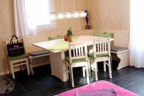 Een houten eethoek met een tafel, stoelen en een bank.