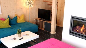 A modern living room with a blue sofa, a pink sofa, a white coffee table, and a fireplace.