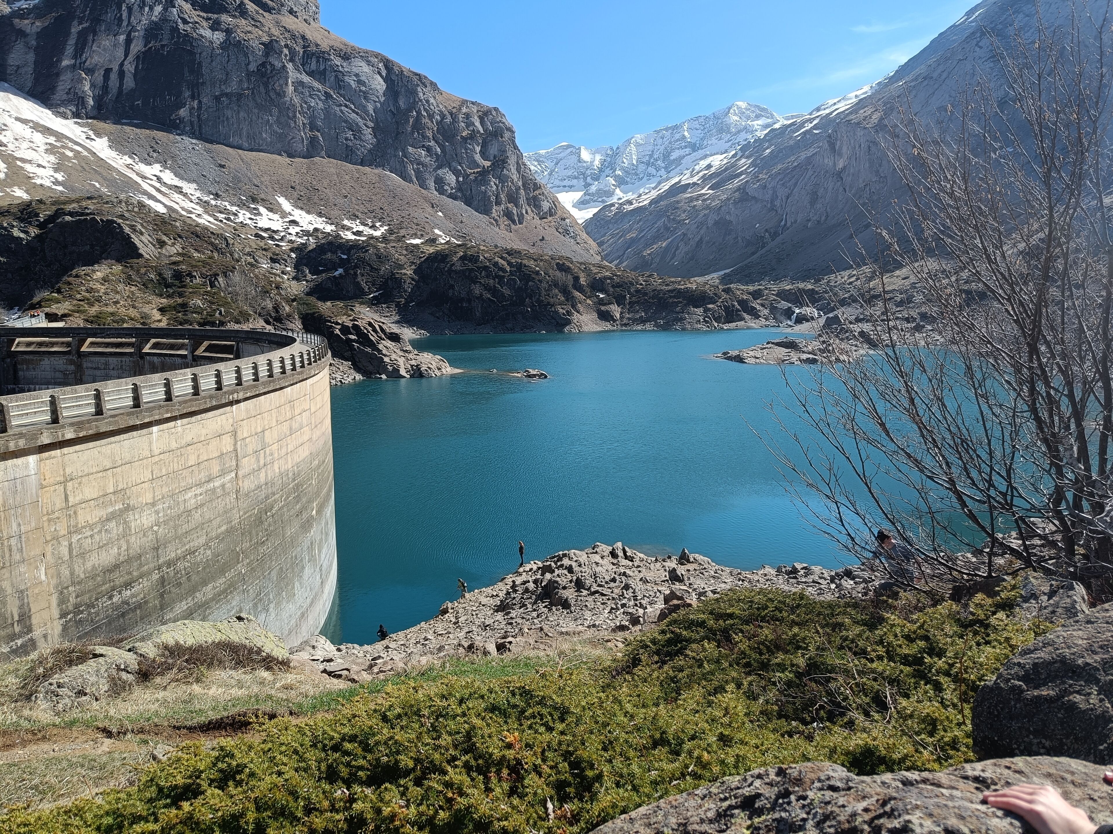 Un grand lac aux eaux d’un bleu profond, bordé de falaises rocheuses et d’une végétation clairsemée.