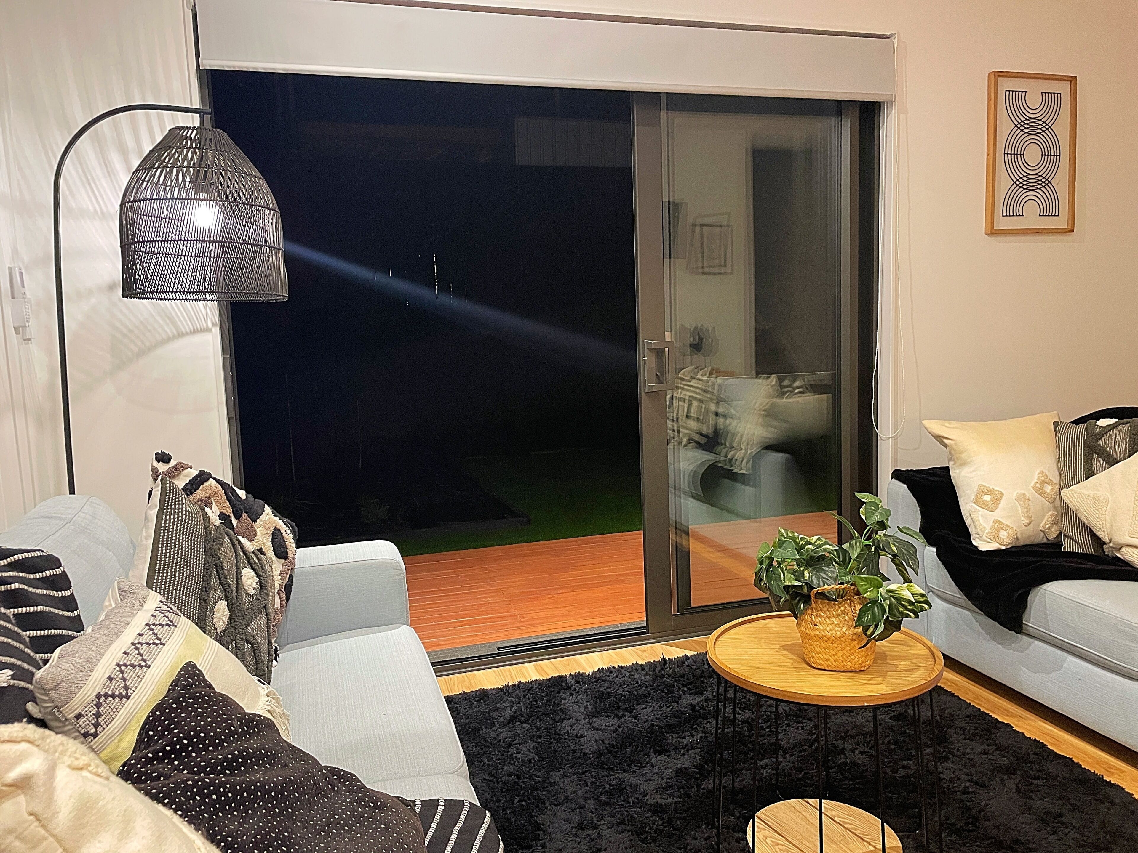 Uma sala de estar moderna com um sofá, uma mesa de centro e uma porta de vidro deslizante que dá para uma varanda.