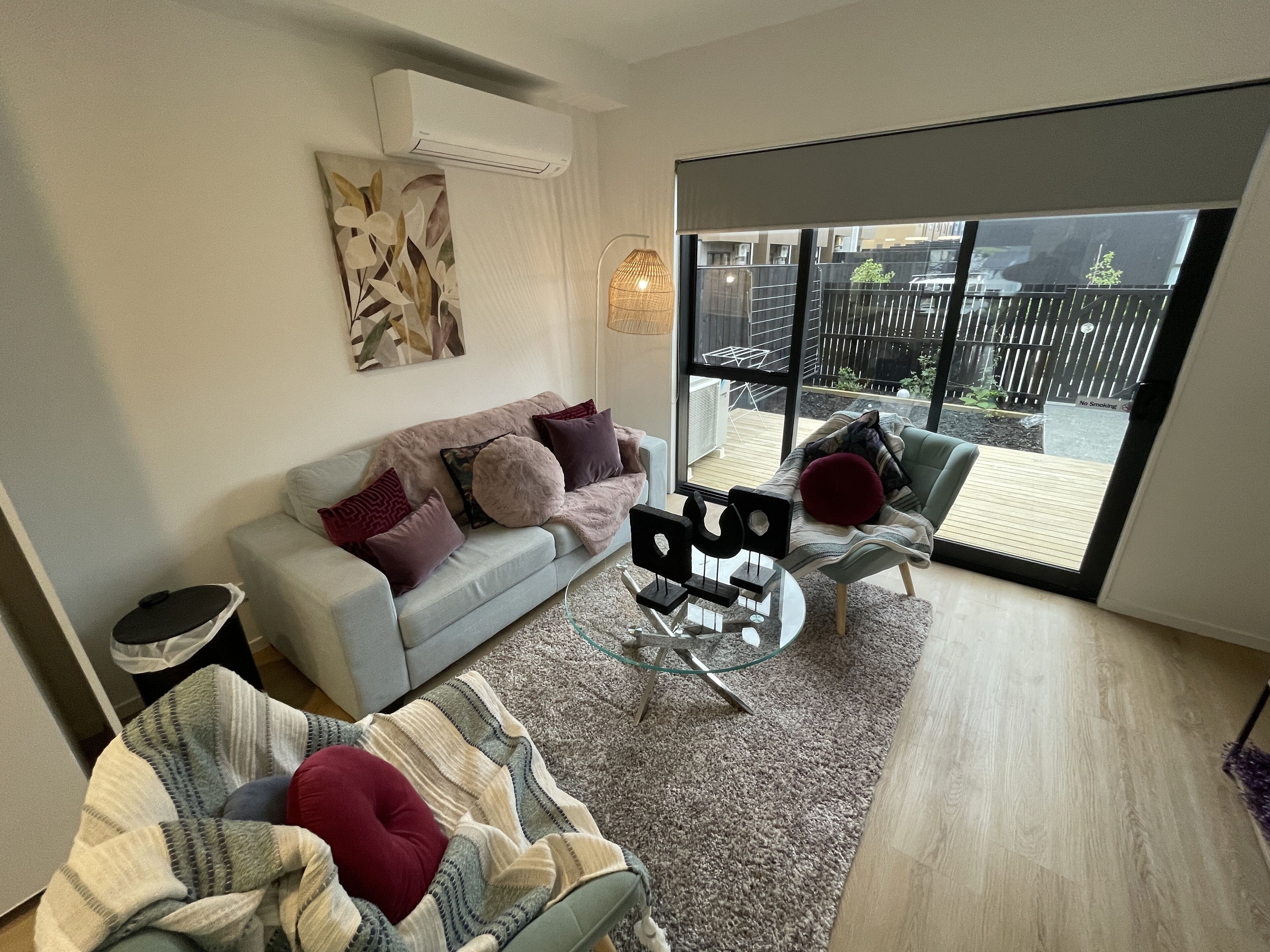 A modern living room with a grey sofa, a striped rug, and a glass coffee table.