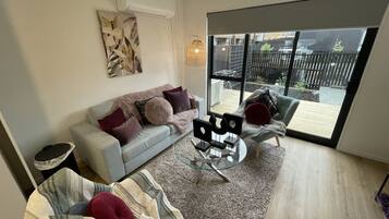 A modern living room with a grey sofa, a striped rug, and a glass coffee table.