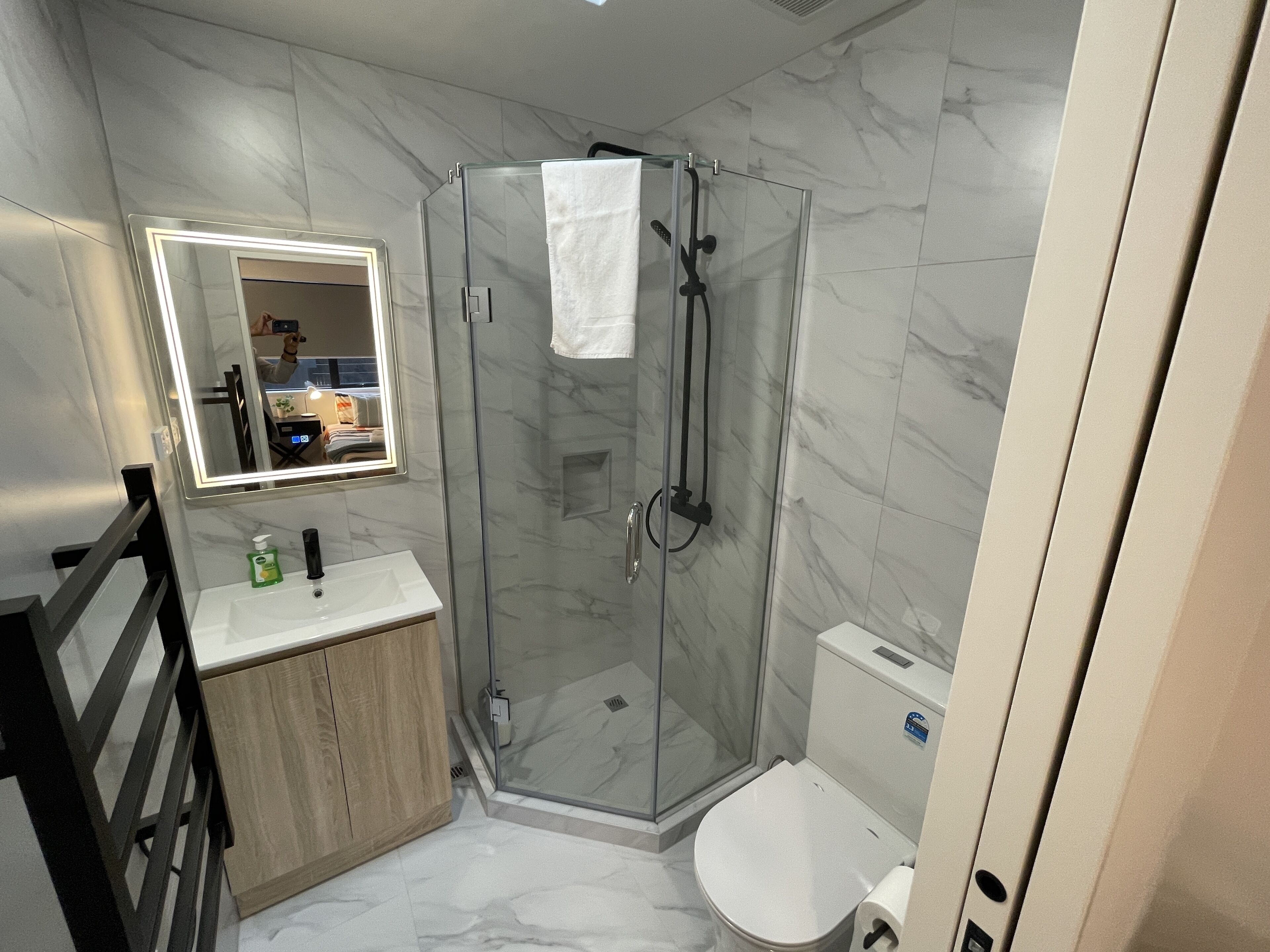 Une salle de bain moderne avec une douche à parois de verre, des toilettes blanches et un meuble-lavabo en bois.