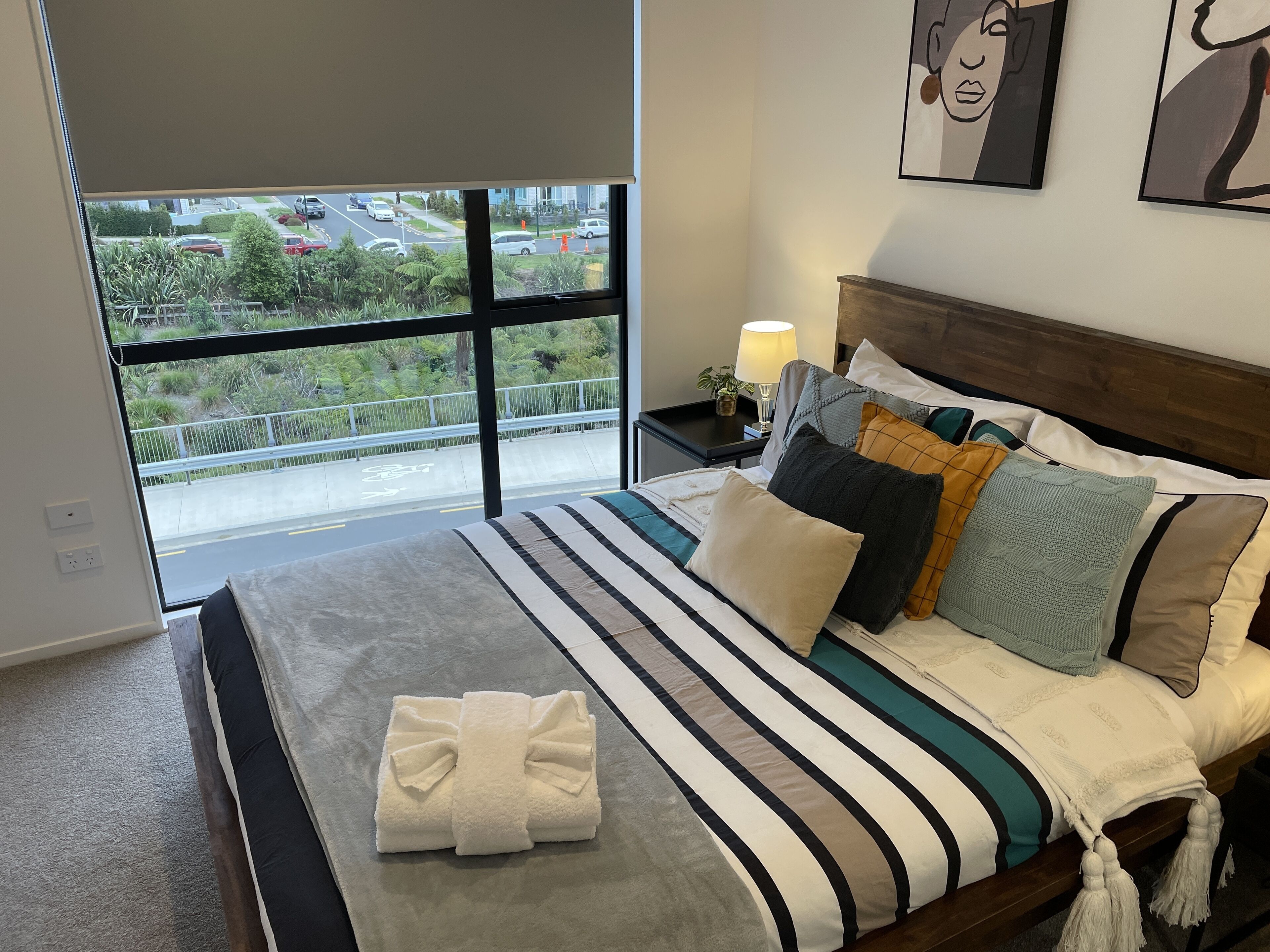 A neatly made bed with striped bedding, a white towel, and multiple pillows.