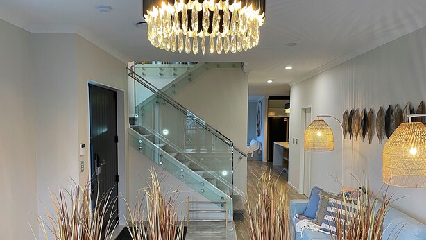 Un interior moderno con una escalera, una araña y plantas decorativas.