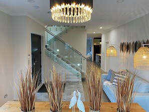 Un interior moderno con una escalera, una araña y plantas decorativas.