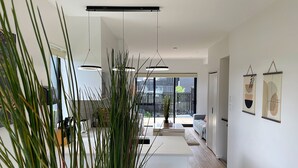 Un interior moderno con suelo de madera, paredes blancas y un ventanal grande.