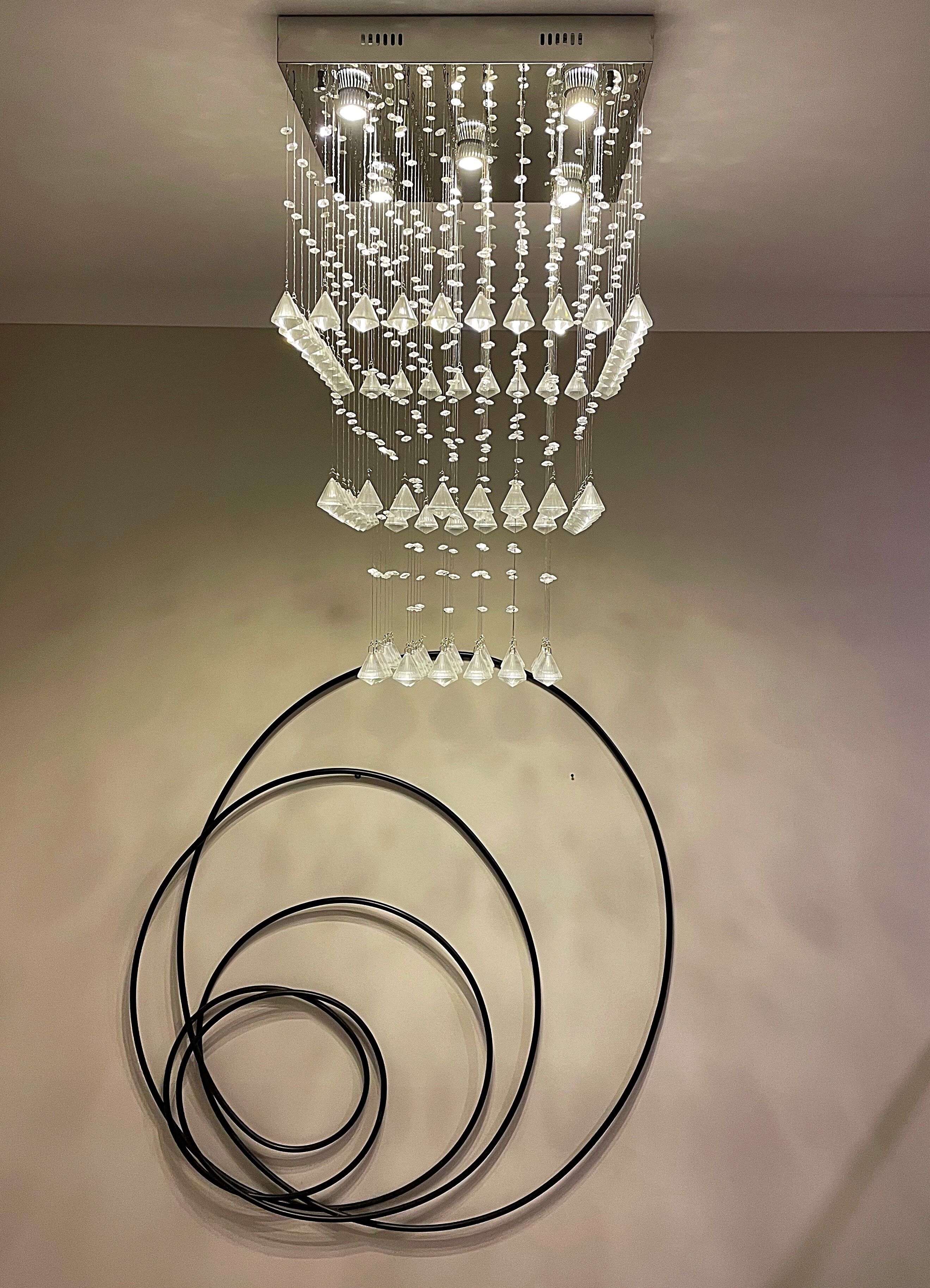 A ceiling with a hanging chandelier and coiled black cables.