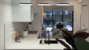 Una cocina moderna con armarios blancos, horno integrado y un amplio ventanal con vistas al jardín.