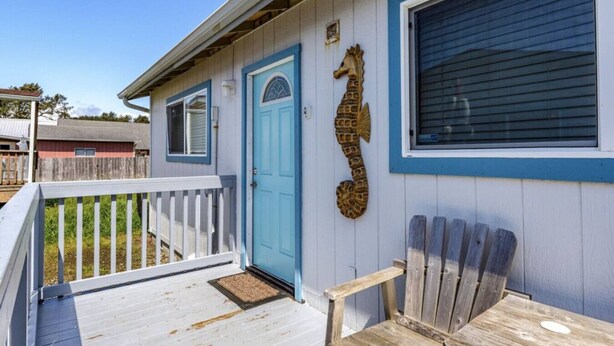 Ein Haus mit blauer Tür, einer Meeresschwangerschaft-Dekoration und einem Holzstuhl auf der Veranda.