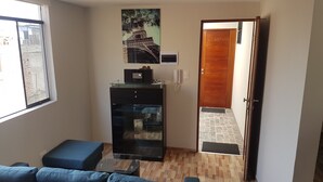 Ein Wohnzimmer mit einem blauen Sofa, einem Glastisch, einer Holzkabine mit einem Bilderrahmen und einer Tür zu einem anderen Raum.