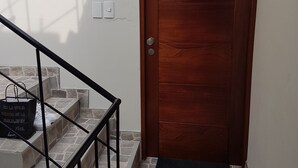 Eine Holztür mit der Nummer 402, eine Steintreppe und eine schwarze Tasche auf den Stufen.