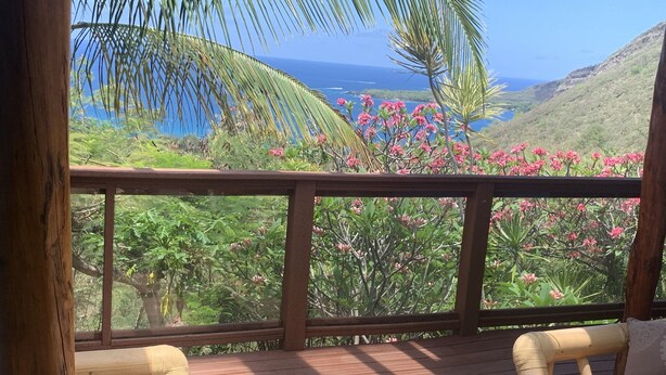 A wooden deck with wicker furniture and a view of a coastal landscape.